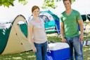Couple carrying cooler at campsite