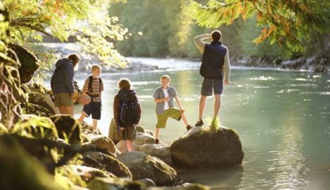Family on hike, standing on rocks next to river