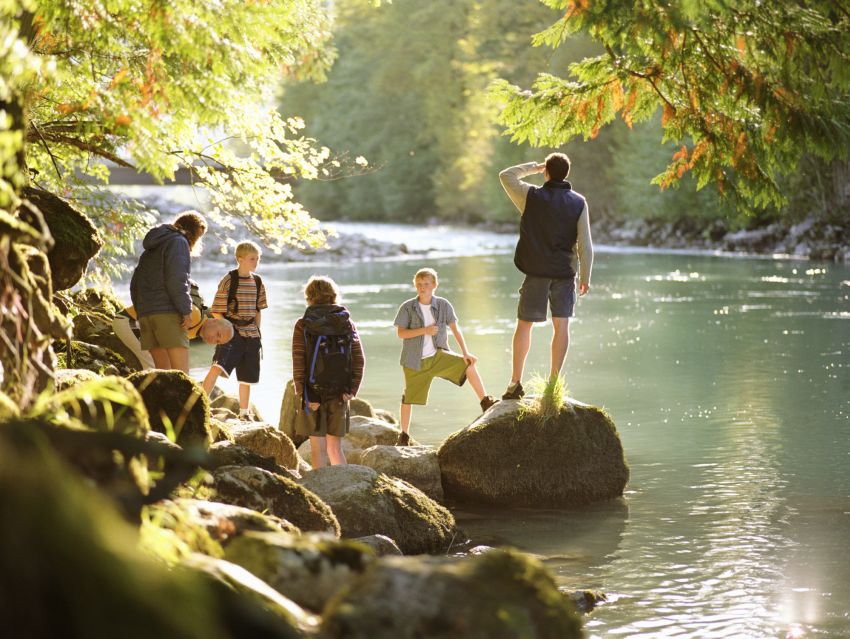 Family on hike, standing on rocks next to river