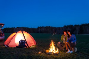 Paar das vor dem Zelt am Lagerfeuer sitzt